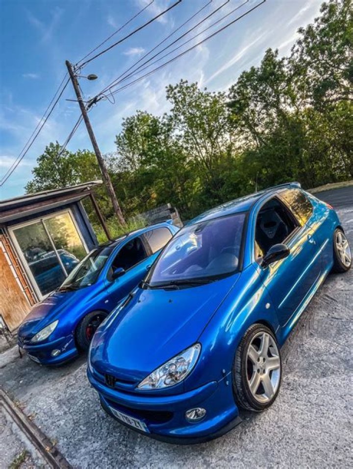 two blue cars parked next to each other in front of a building with